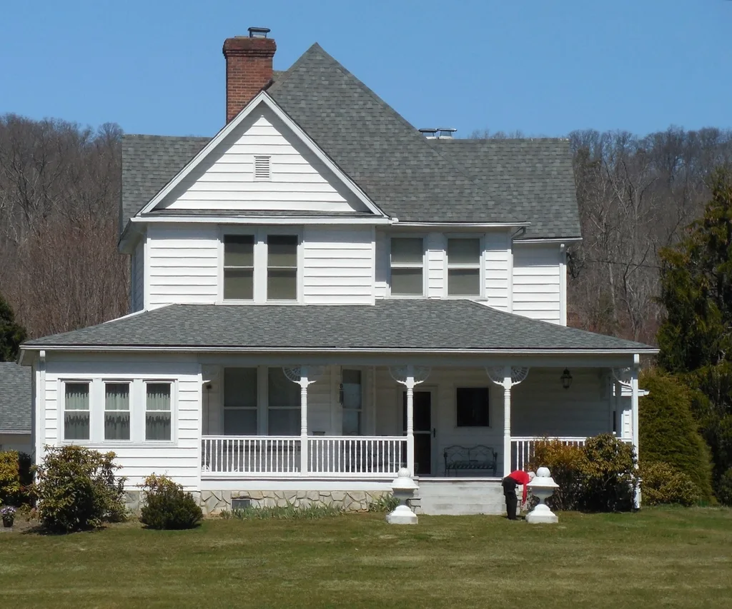 White two-story house with a wraparound front porch