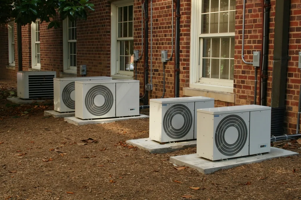 Row of outdoor air conditioning condensers beside a brick building