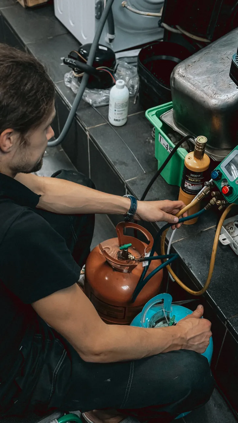 HVAC technician connecting refrigerant gauges and cylinders